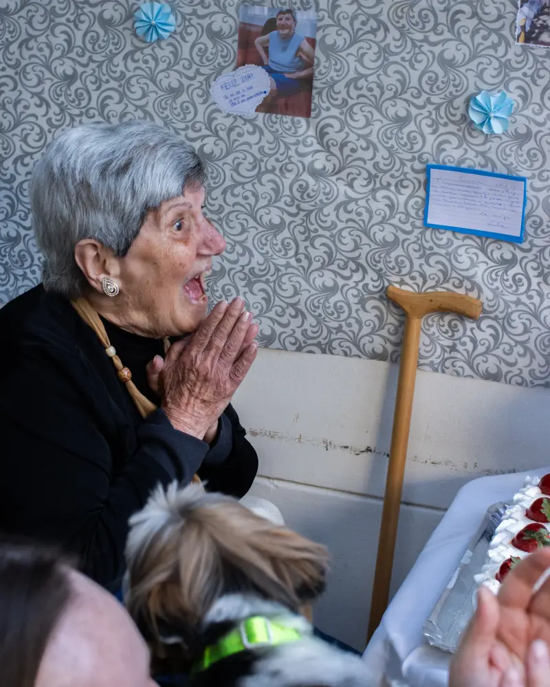 Residente emocionada diante do bolo na sua festa de aniversário