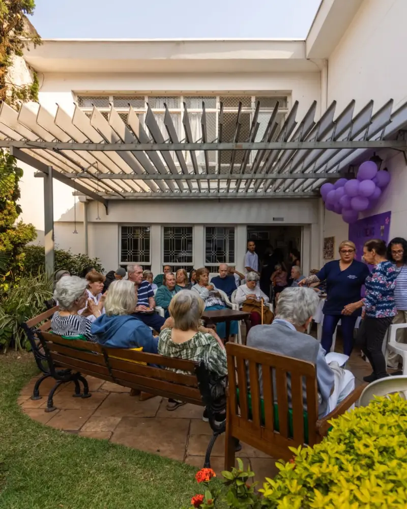 Residentes e familiares reunidos no pátio em uma festa com balões